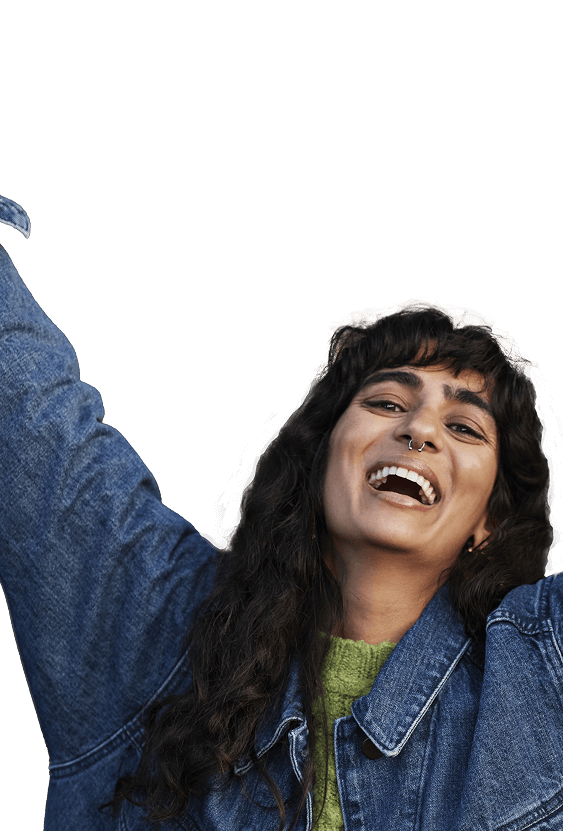 Smiling woman with arms raised, wearing a denim jacket.